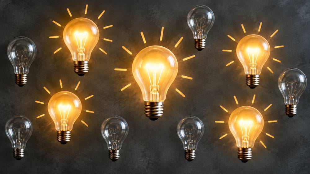 Bright lightbulbs on black background, depicting ideas